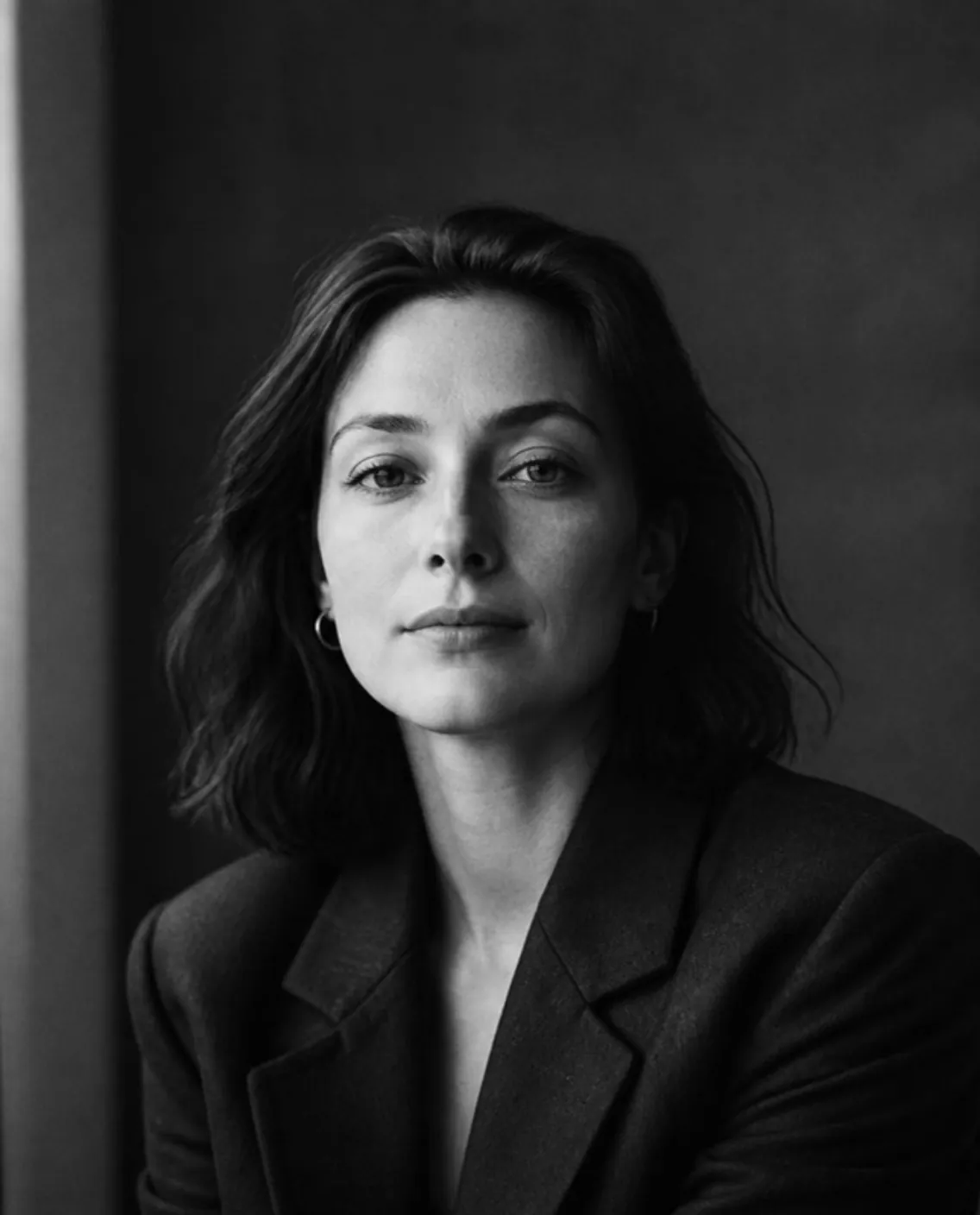 Black-and-white portrait of a woman with shoulder-length dark hair in a dark blazer, looking calmly into the camera